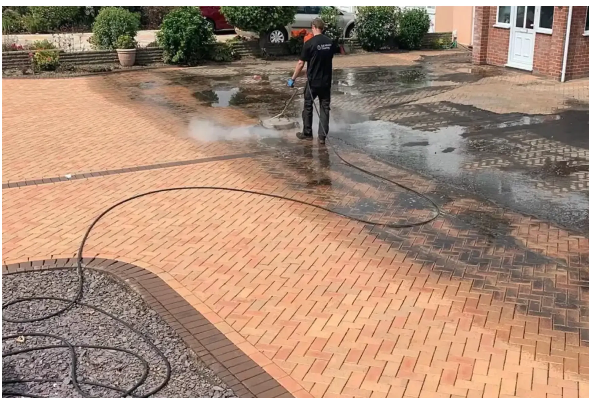 Technician using a rotary surface cleaner on a brick paved driveway