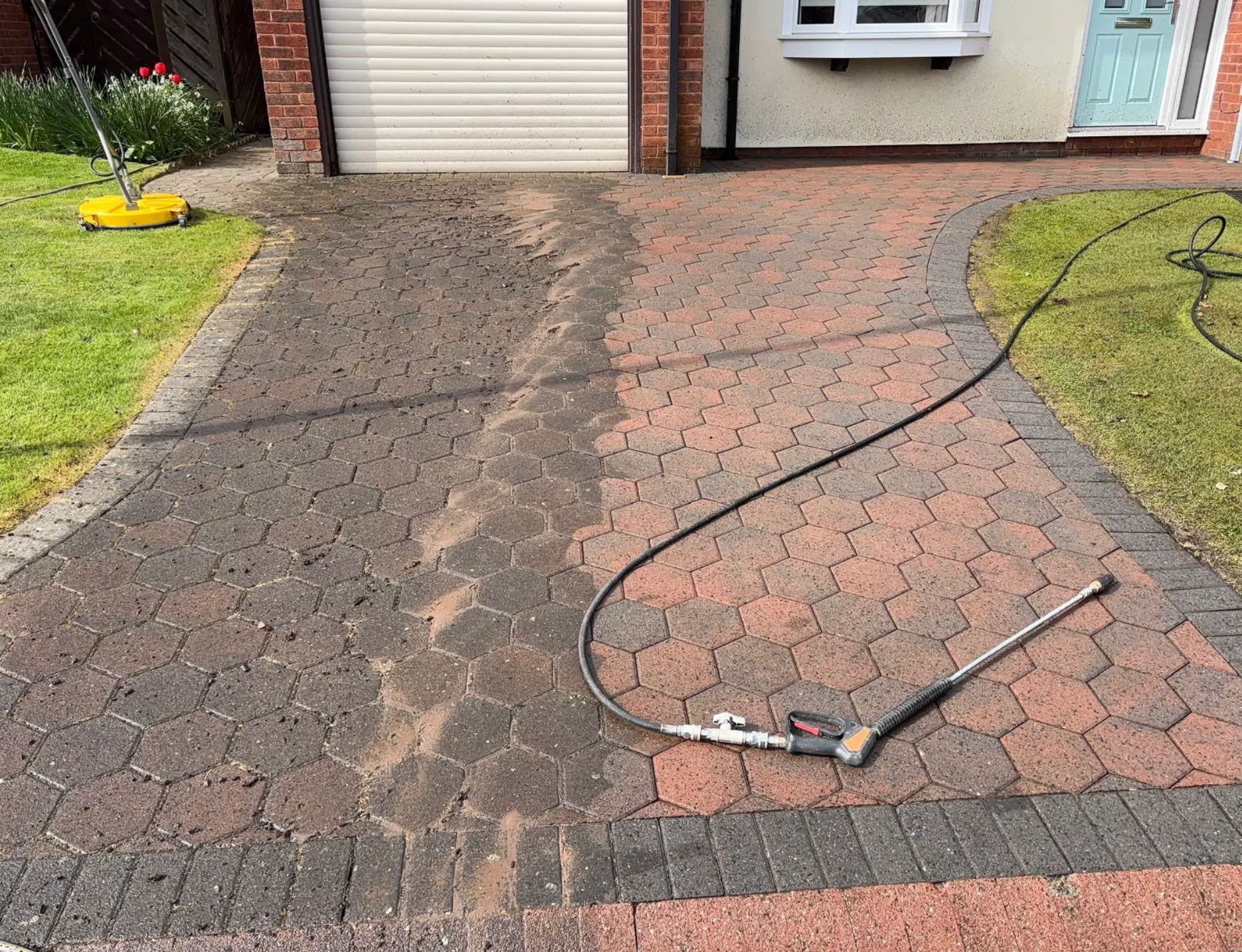 Half-cleaned hexagonal block paving driveway showing dirt removed on one side